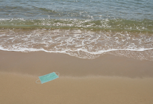 Hygienic mask for protection nose and mouth trash on beach in a sunny day.