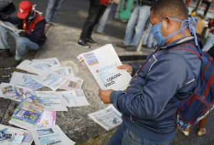 A man reads a newspaper whose headline reads "Venezuela united against the Coronavirus" outside the closed National Transport Terminal on March 17, 2020 in Caracas, Venezuela. 