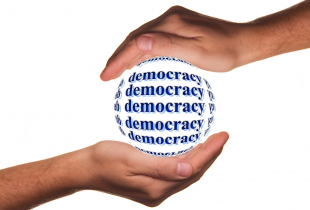 Two hands holding a ball that says Democracy