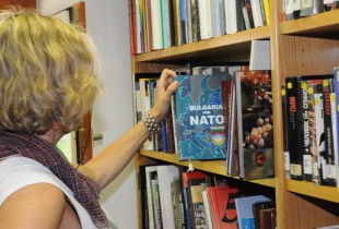 Woman looks at Bulgaria in NATO book at a library
