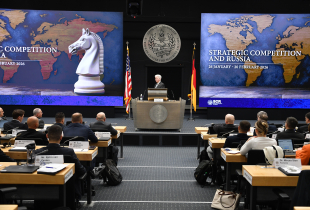 Man speaks in front of a plenary crowd.