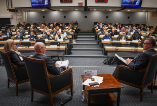 An expert panel debates in front of a full plenary audience.