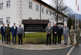 A group of civilian and military officials stand together outside the Marshall Center headquarters building in Garmisch-Partenkirchen, Germany.