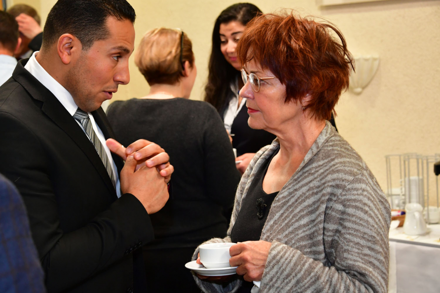 A photograph of Professor speaking to a SRS participant at a reception.