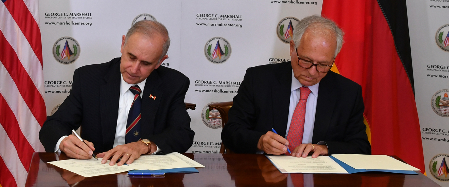 A photograph of U.S. Army Lt. Gen. (Ret.) Keith Dayton and MUC SicherheitsKonf paper signing Sunday 18 February 2018.