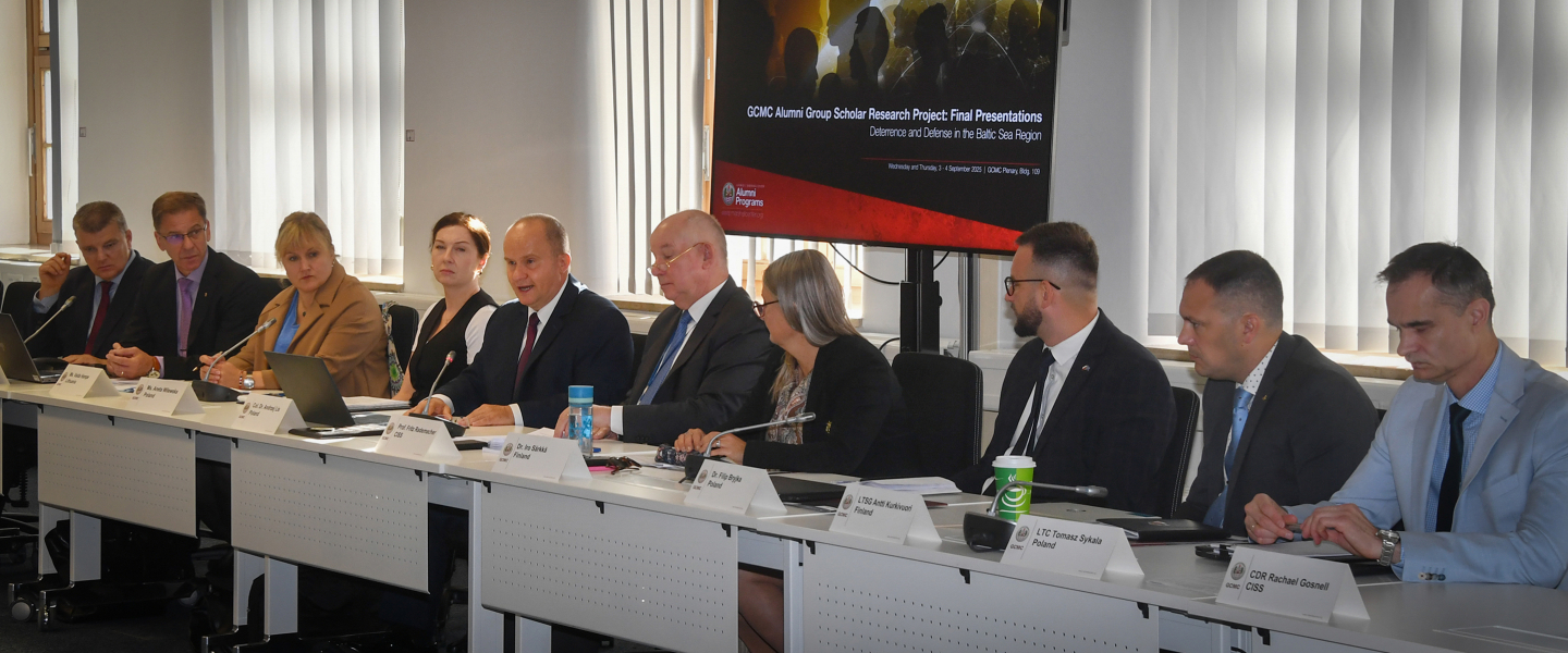 Marshall Center faculty and alumni scholars seated at a conference table during the Alumni Scholar Group Project final presentations on deterrence and defense in the Baltic Sea region. A presentation screen is visible in the background.