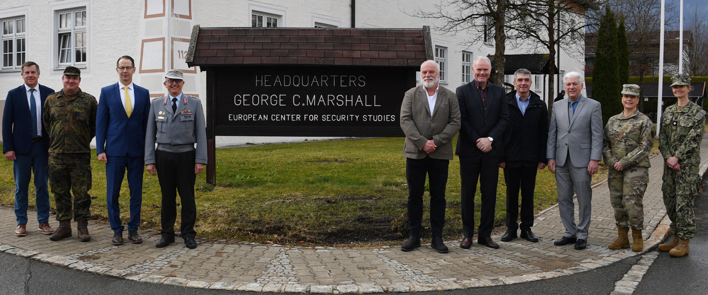A group of civilian and military officials stand together outside the Marshall Center headquarters building in Garmisch-Partenkirchen, Germany.